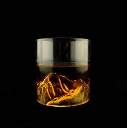 Verre transparent avec un relief de montagne visible sous une boisson ambrée