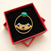 Boucle d’oreille circulaire en malachite et lapis-lazuli présentée dans sa boîte rouge
