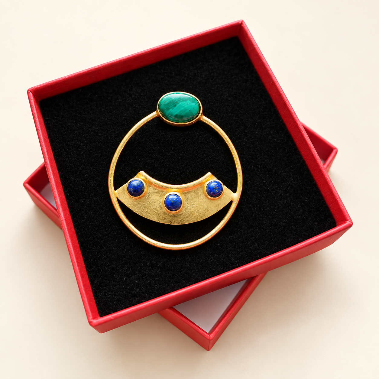 Boucle d’oreille circulaire en malachite et lapis-lazuli présentée dans sa boîte rouge