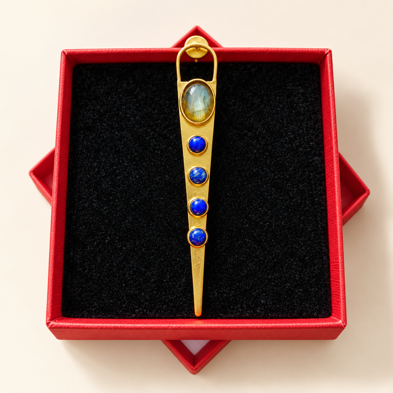 Boucle d’oreille longue en forme de flèche aux détails bleus dans sa boîte rouge